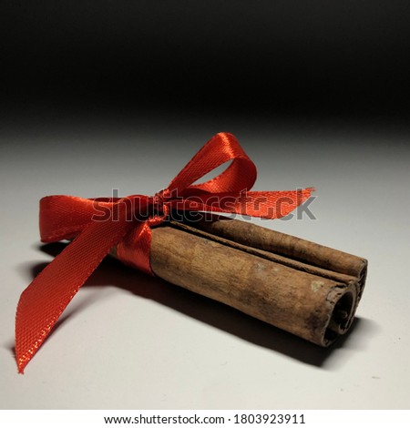 Close-up studio object picture of natural brown cinnamon roll with red tape on the white surface with black background