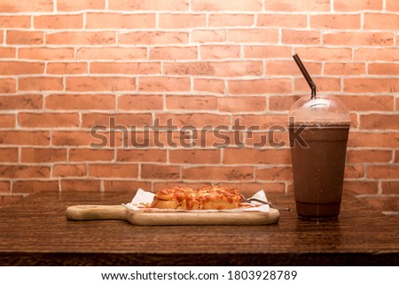 Pizza toast with cocoa smoothie on a wooden table.