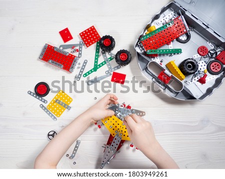 Kid constructing model with metal constructor details. Kids hands. Top view. Royalty-Free Stock Photo #1803949261