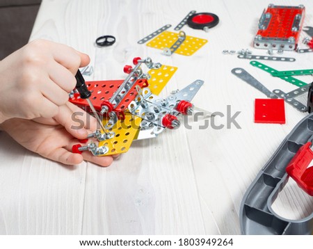 Kid constructing model with metal constructor details. Kids hands. Top view. Royalty-Free Stock Photo #1803949264