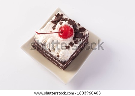 Chocolate layer cake with cherries on top on white background