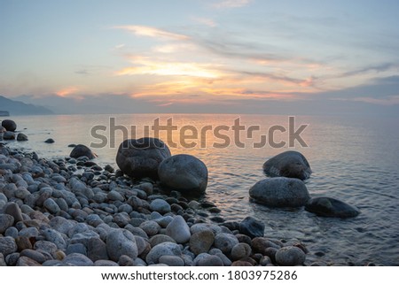 
Three large stones above the water surface at sunset