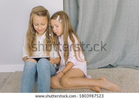 Little girls watching cartoons on tablet at home. Copy space.