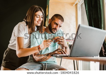 Couple buying online with credit card and laptop in a coffee shop