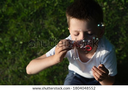 blurred concept image with soap bubbles, boy blowing soap bubbles