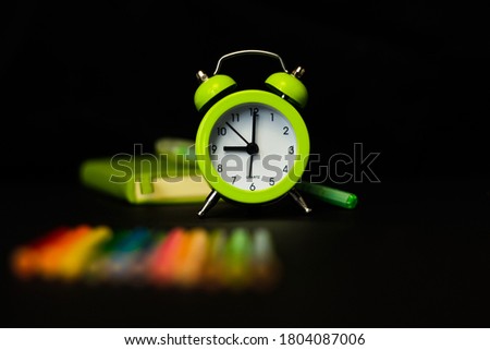 Light green alarm clock on a black background. Back to school. Time in school.
