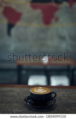 Hot coffee latte on the table with world map on the wall as a background 