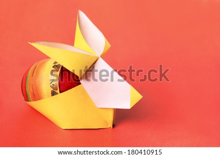 Easter bunny paper rabbit with painted egg on a orange background