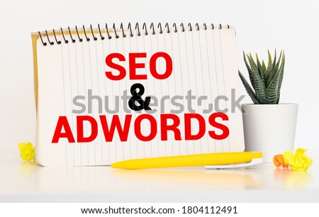 Word writing text Seo And Adwords. Business concept for Pay per click Digital marketing Google Adsense Stationary and torn cardboard placed above a wooden classic table backdrop.
