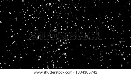 Strong snow blast at night. It shows shiny snowflakes falling from the sky fast against an isolated black background