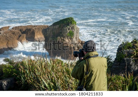 Japanese senior man taking pictures of Pancake Rocks, Punakaiki, South Island, New Zealand