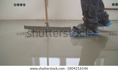 Interior of apartment under construction. Mirror smooth surface of the floor. Floor covering with self leveling cement mortar. Roller application Royalty-Free Stock Photo #1804216546