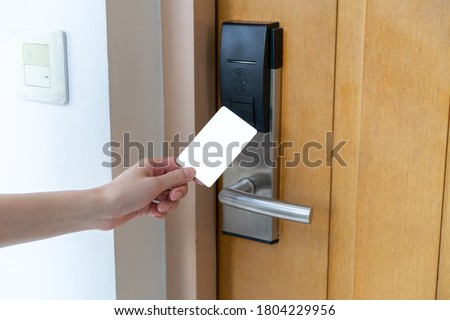 Door access control - woman hand holding white mockup key card to lock and unlock door. digital door lock.