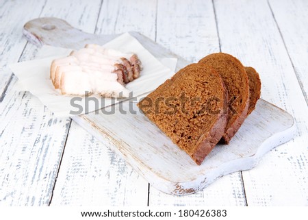 Slices of bread and lard on cutting board on wooden background