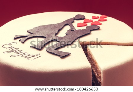 White round cake on red background, decorated with male and female silhouette of sugar on top. 