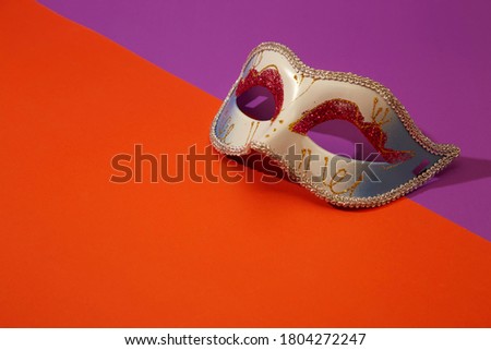 Close up of Mardi Gras or Carnival mask on a bright orange and violet background, Flat lay accessory carnival festival