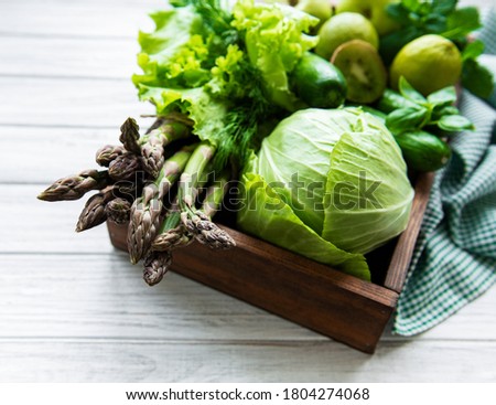 Healthy vegetarian food concept background, fresh green food selection for detox diet, box with  apple, cucumber, asparagus, avocado, lime,  salad  top view on a white wooden  background