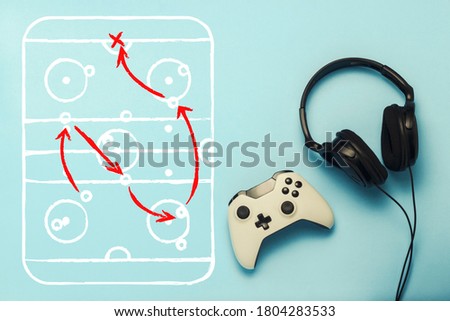 Headphones and gamepad on a blue background. Added drawing with the tactics of the game. Hockey. The concept of computer games, entertainment, gaming, leisure. Flat lay, top view.