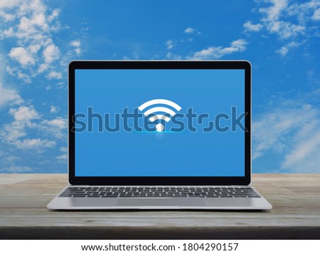 Wi-fi flat icon with modern laptop computer on wooden table over blue sky with white clouds, Technology internet online concept