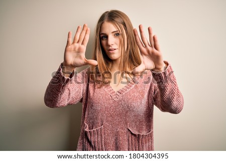 Young beautiful redhead woman wearing pink casual sweater over isolated white background doing frame using hands palms and fingers, camera perspective