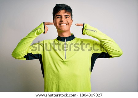 Young handsome sportsman doing sport wearing sportswear over isolated white background smiling cheerful showing and pointing with fingers teeth and mouth. Dental health concept.