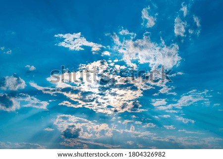 Dramatic sky with colorful clouds at sunset. Beautiful morning sky painted in bright and warm colors. Sun behind the clouds. Sun rays.