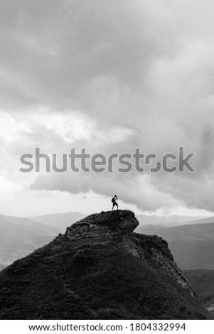 Hiker photographing the landscape from top of the mountain with cloudy sky at evening. Active outdoors person. 