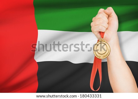Sportsman holding gold medal with flag on background - United Arab Emirates