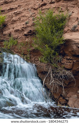 waterfall among clay rocks and dry branches. Bubbles from water pressure