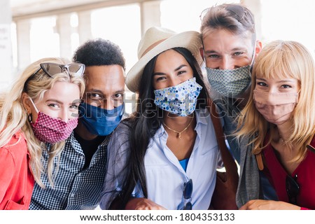 Portrait group of young happy friends wearing face mask during Covid pandemic smiling at the camera. Multiracial people taking a selfie outdoor having fun together. New normal lifestyle concept. Royalty-Free Stock Photo #1804353133
