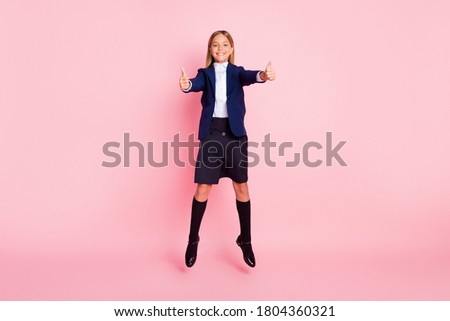 Photo of cute pretty small lady smile jumping show thumbs-up approve classmate subject choice wear uniform blue jacket shirt skirt black stockings isolated pink color background