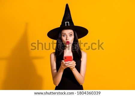 Halloween almost canceled. Photo of cute lovely young magician lady hold telephone amazed theme event postponed wear black wizard headwear dress isolated bright yellow color background Royalty-Free Stock Photo #1804360339