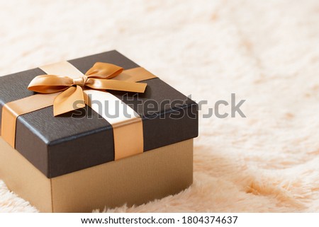 Beautiful golden box on a cream fur blanket. Surprises, gifts, bonuses, discounts concept. Blank for advertising or design, copy space