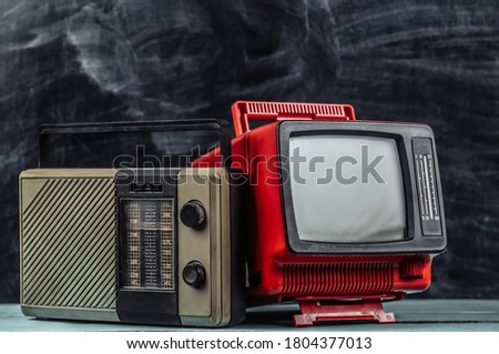 Retro media. Old school portable tv, radio receiver on blackboard background