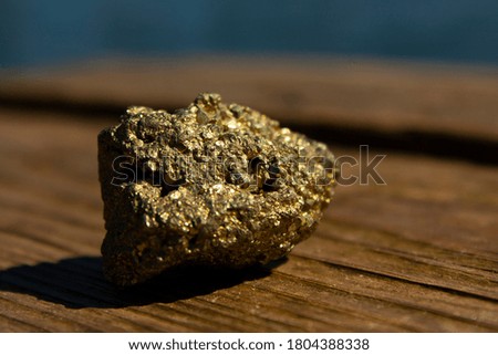 Close-up object picture of an isolated yellow shiny stone laying on the wooden surface
