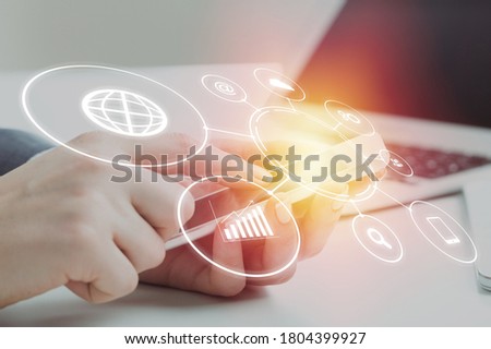 Human hands with smartphone working on laptop on office desk