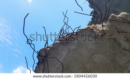 Destruction of a concrete structure with reinforcement against a blue sky background. Old concrete floor of an abandoned building