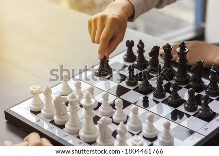 Two people playing chessboard together, the black side walking chess pieces.