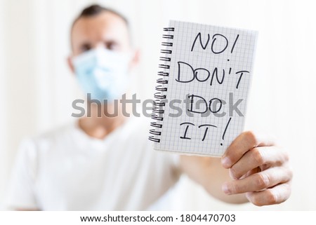 a man shows a sheet of paper with the inscription NO DONT DO IT