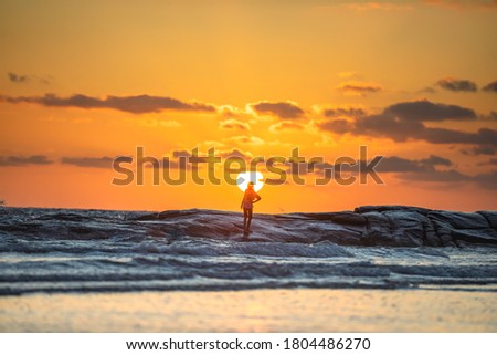 A young girl was standing on a rock and blurring the background of the sunset.Silhouette picture style.