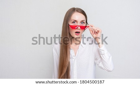 Surprised young girl takes off his pixel glasses, portrait, white background, 16:9