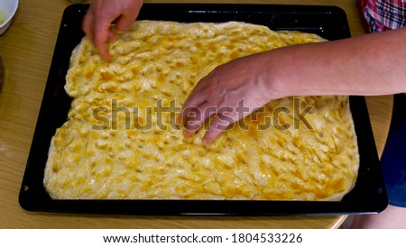 Female hands lay the dough in a baking tray, prepare bread with olive oil. Dough for bread. Preparing Pizza