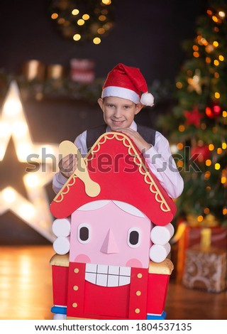 Teenager with a toy nutcracker in the studio for the new year. Christmas tree in the lights of the garland.