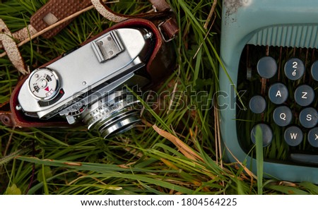 Old vintage photocamera and typewriter on the green grass 