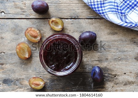 Plum jam and fresh plums on wooden table