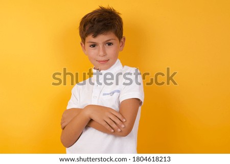 Waist up portrait of young handsome caucasian little boy with positive expression, has crossed arms, feels happy and confident, wears casual clothes, isolated over gray background.