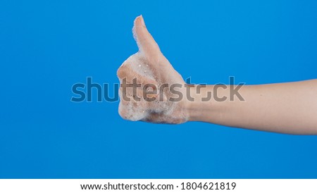 Soapy young woman's hand making the sign that everything is fine.Blue background.
