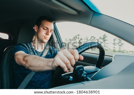 Tired driver falls asleep while driving car. Sleepy man wearing seat belt in vehicle. Risk of accident due to alcoholic intoxication. Unsafe driving from fatigue or drunkenness. Royalty-Free Stock Photo #1804638901