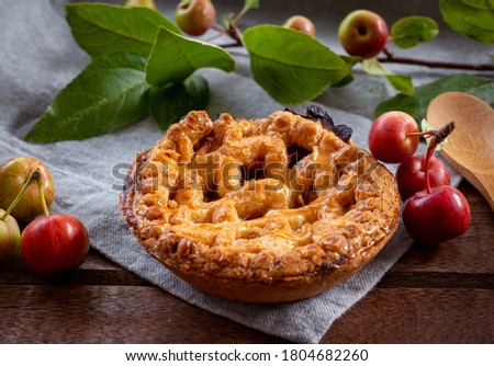 Picture from above of traditional american dessert baked homemade mini apple pie in a wooden box top view decorated with small red wild apple. copy space 