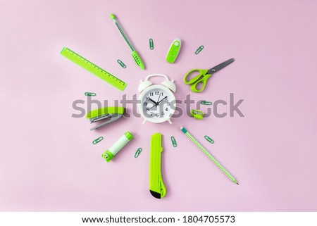 Аlarm clock and green school supplies on pink background. Time for learning. Top view, flat lay
